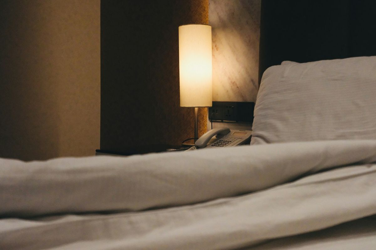 A lit bedside lamp beside a bed at night