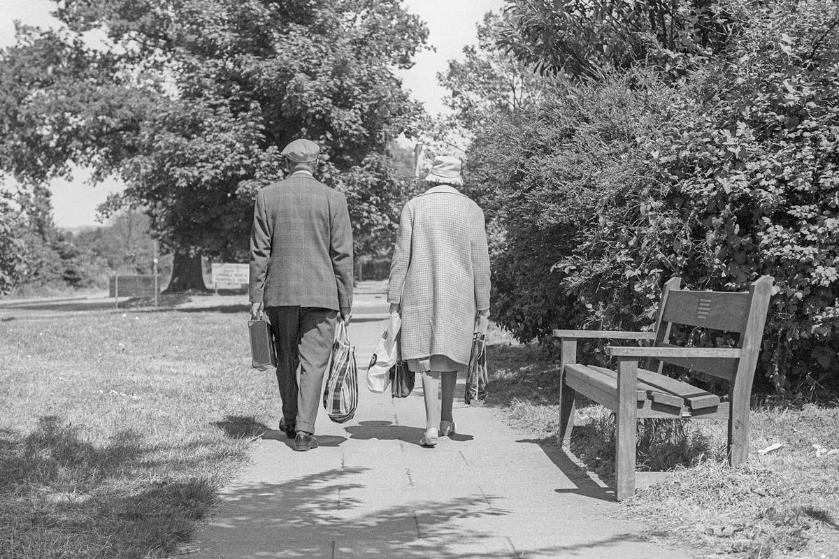 An older couple walking together through a park