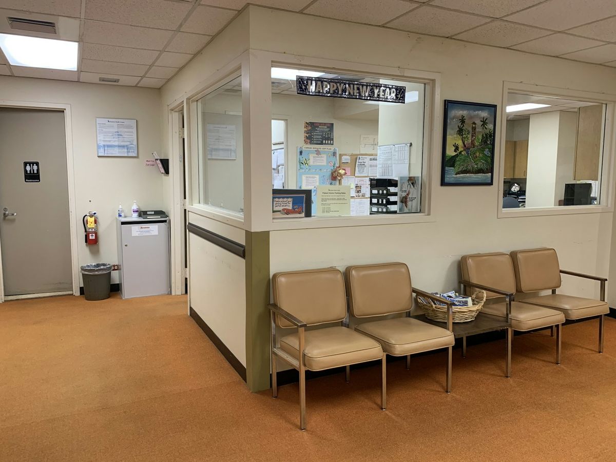 Empty padded chairs beside a reception window in a quiet waiting room
