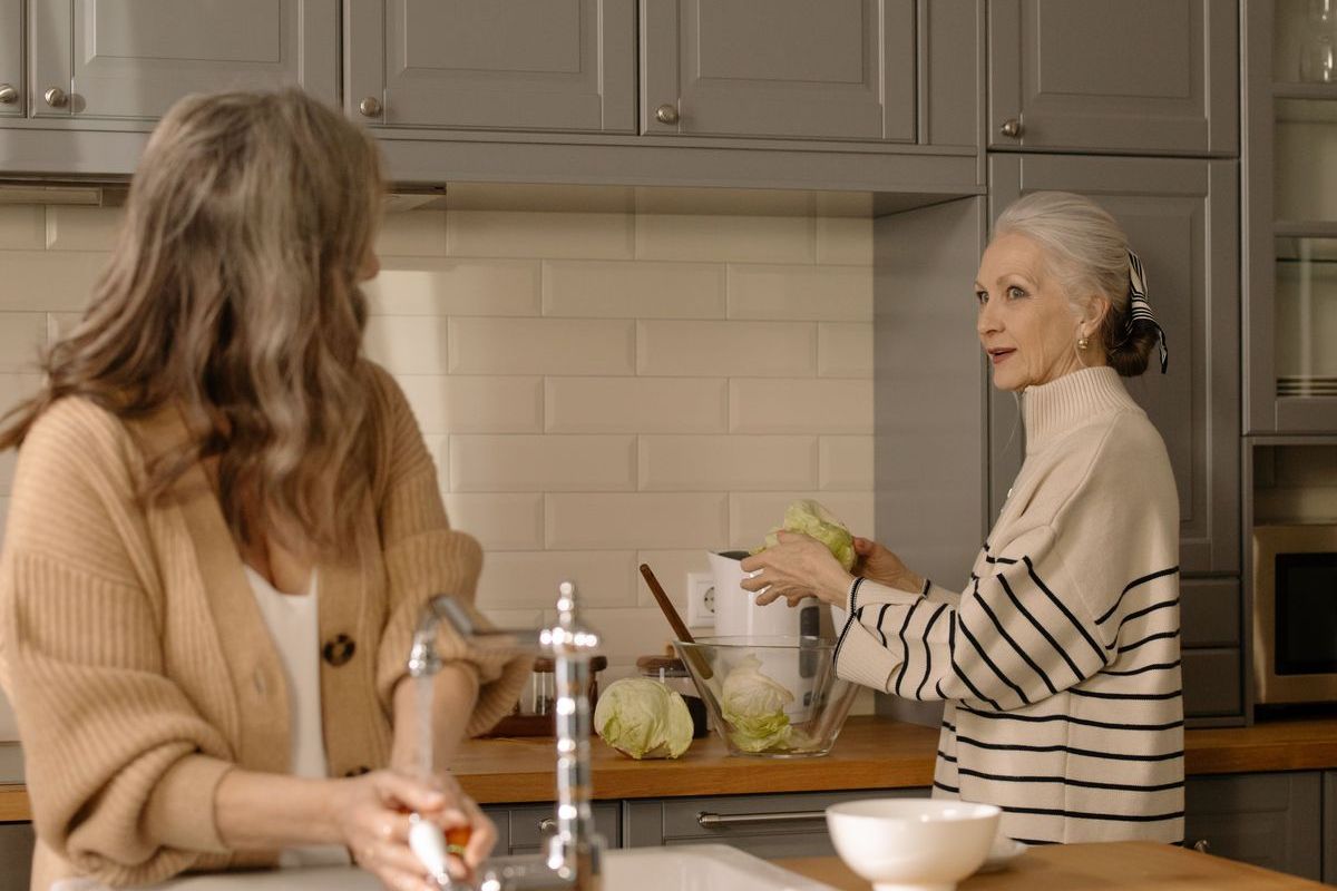 An older woman talking with a younger woman in a kitchen at home