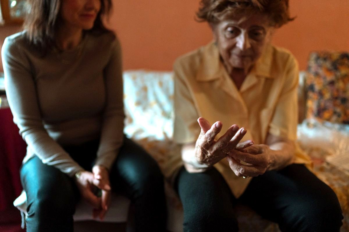 An older woman and a younger woman sitting together on a sofa at home