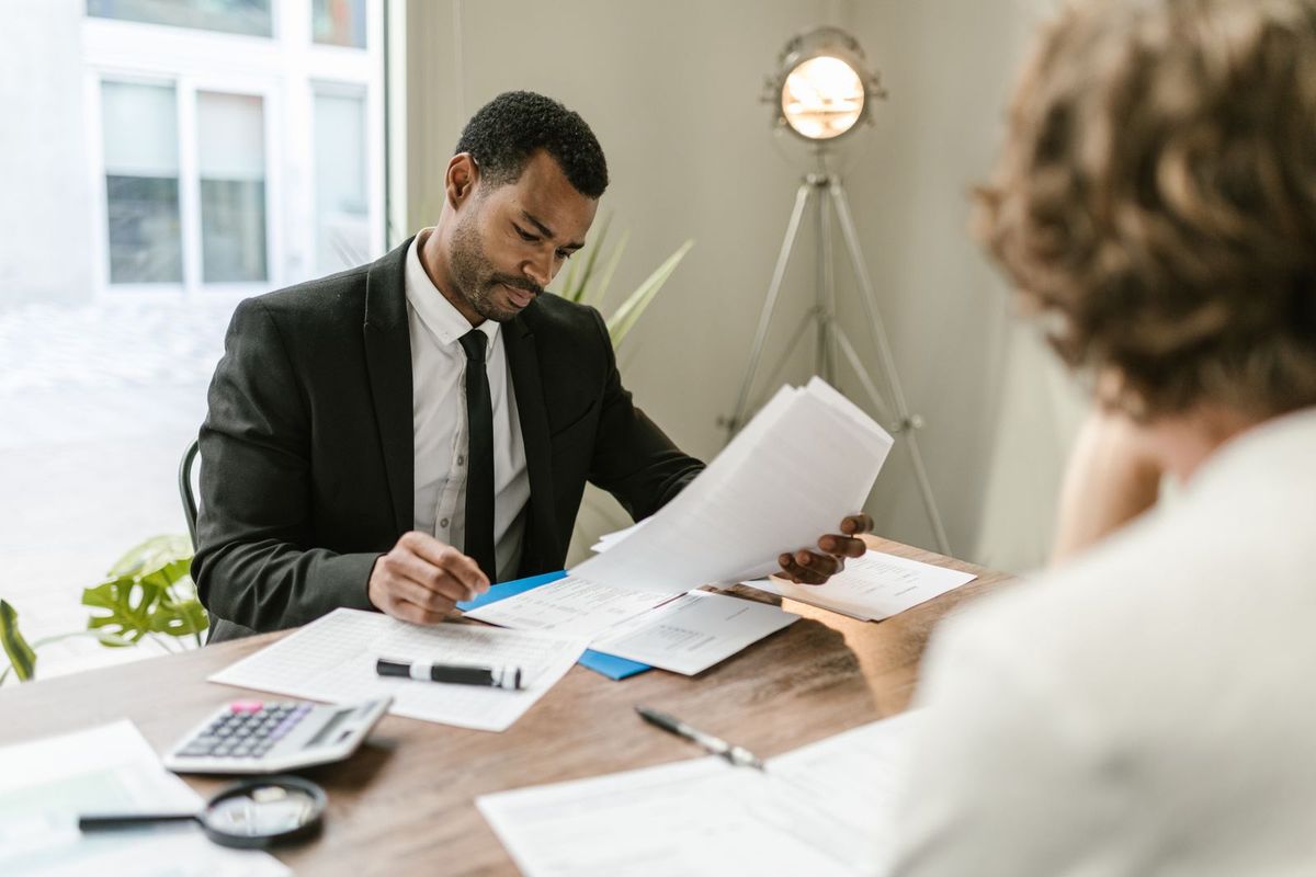 A man in a suit reviewing documents across a desk during a meeting