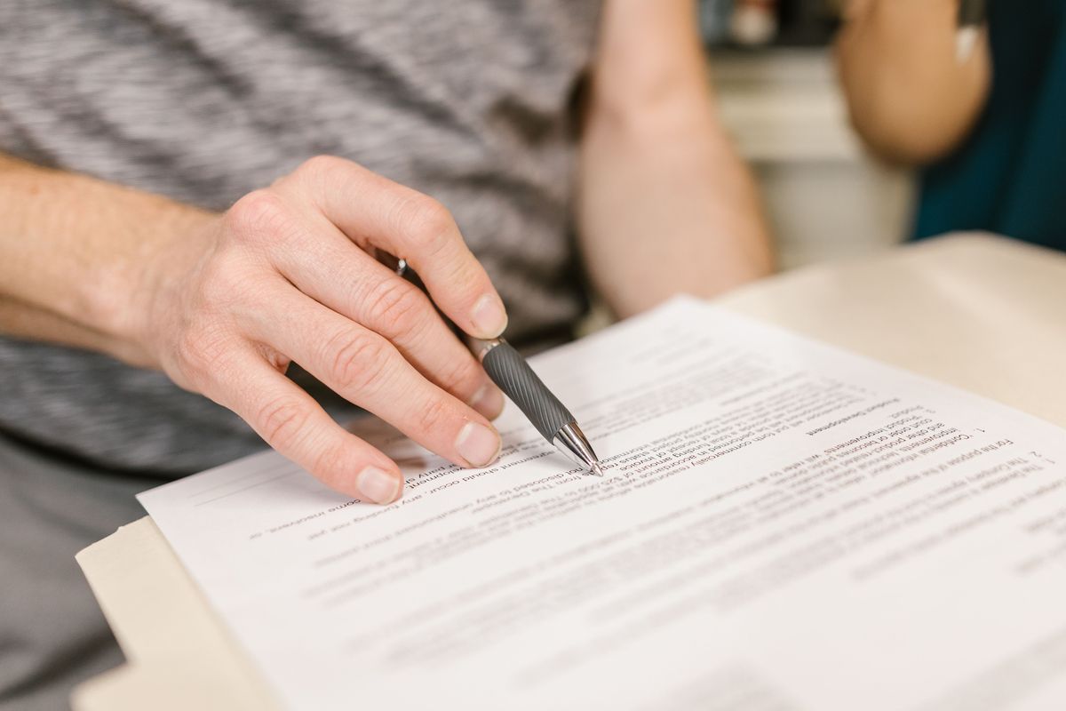 A hand holding a pen over a printed document on a table