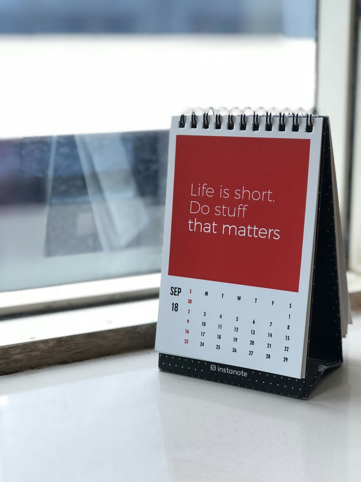 A freestanding spiral calendar on a white desk