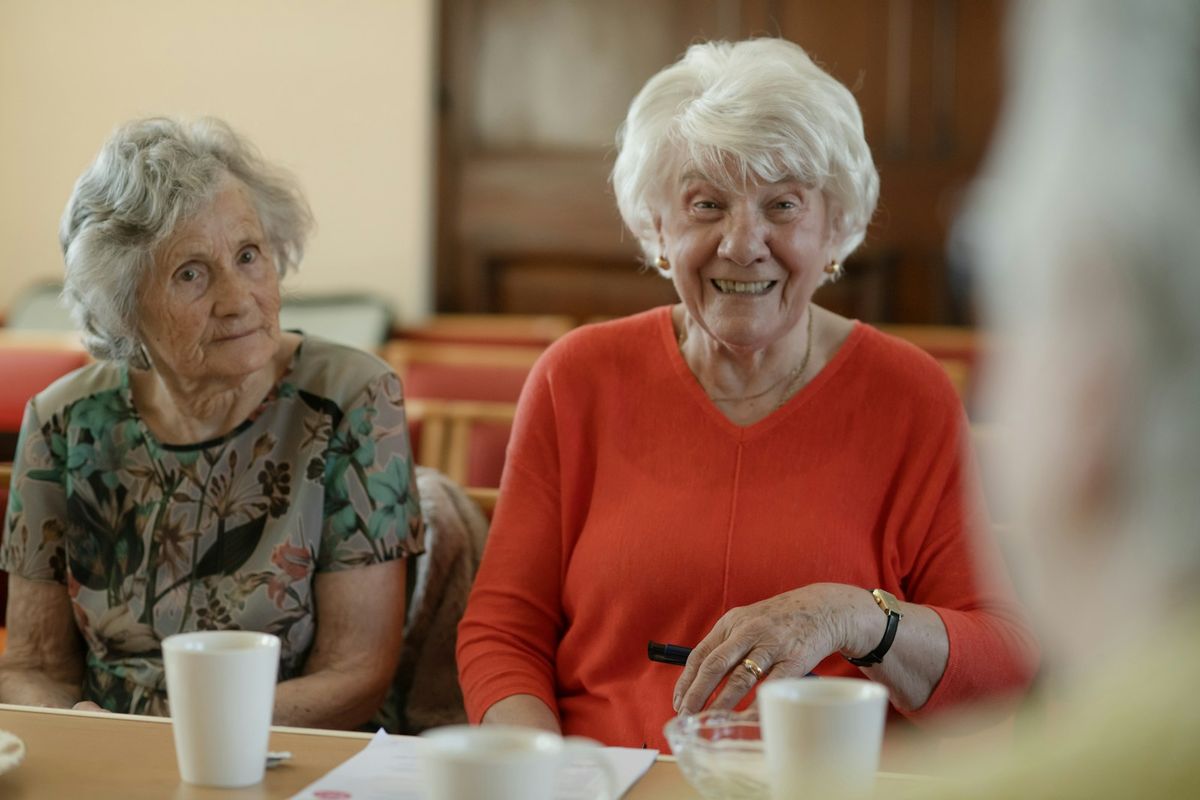 Two older women sitting at a table smiling